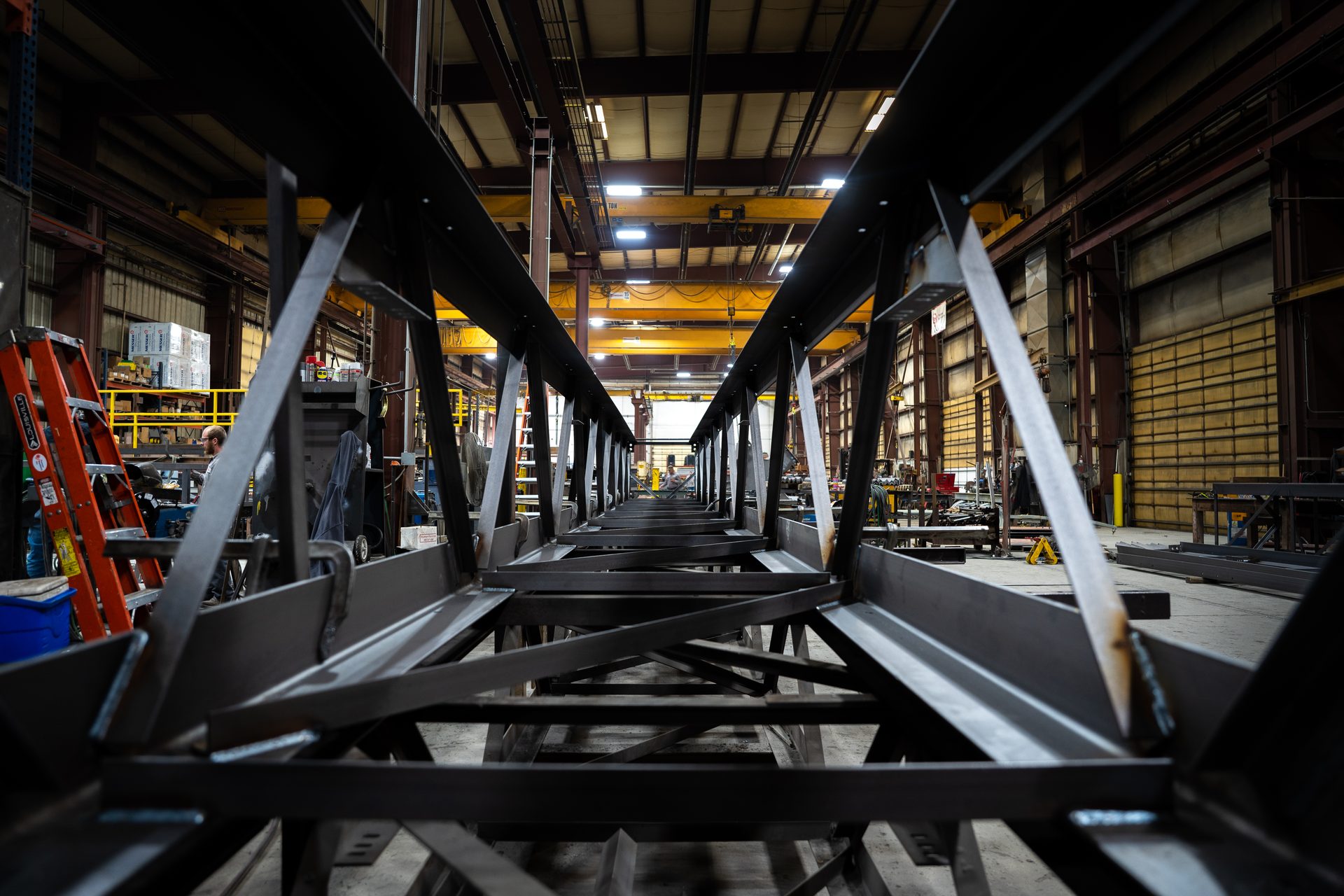 View down the length of a long steel conveyor truss being built in the PMI fabrication shop